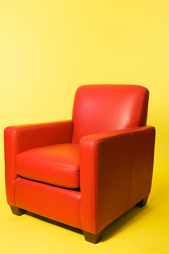 Red leather armchair isolated on yellow background.