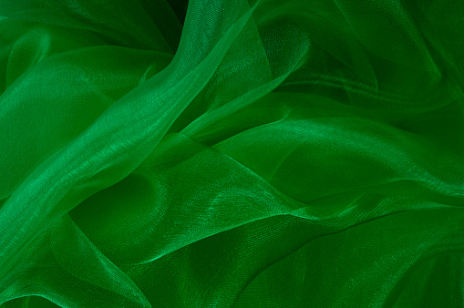 Green fabric flows softly throughout this subtly lit abstract background.