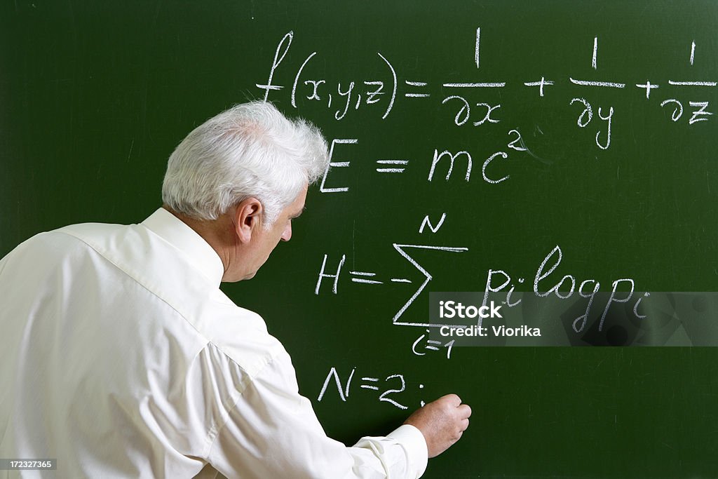 Professor at the blackboard Lecturer writing some formulas on a chalkboard. Chalkboard - Visual Aid Stock Photo