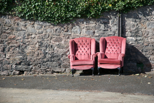 Pink velvet armchairs nestled together outside against stone wall