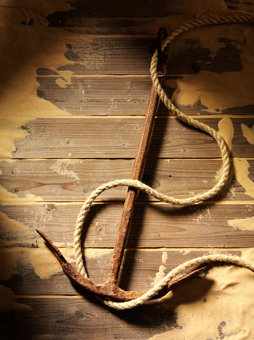 Old rusty ships anchor on a wooden decking background with sand and copy space.Click on the link below to see more of my holiday/travel and nautical images