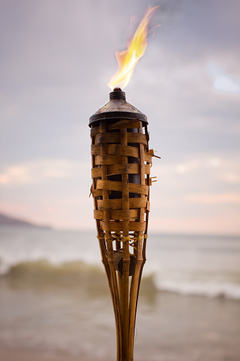 Tikki torch on the beach at sunset.