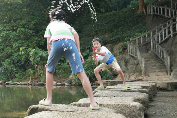 Boy playing in the river with water gun