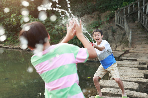 Boy playing in the river with water gun