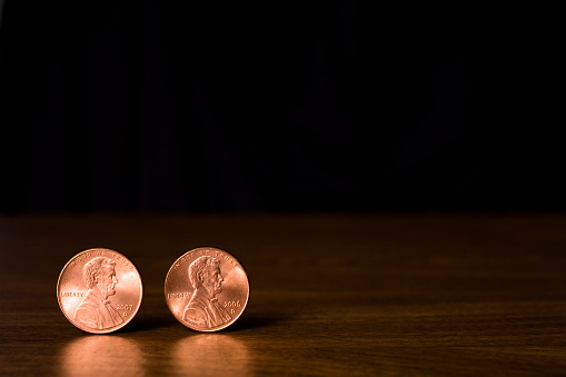 Two copper Lincoln head pennies against black background