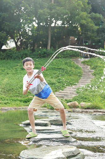 Boy playing in the river with water gun
