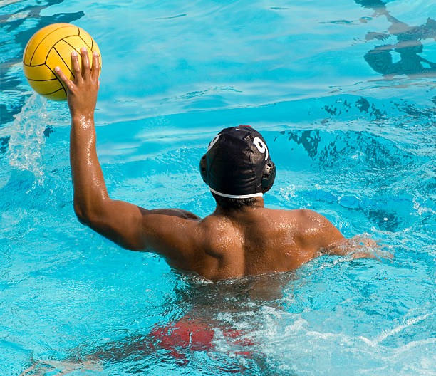 Water Polo Player Fit man getting ready to throw the ball in a game of water polo.  Some motion blur. water polo photos stock pictures, royalty-free photos & images