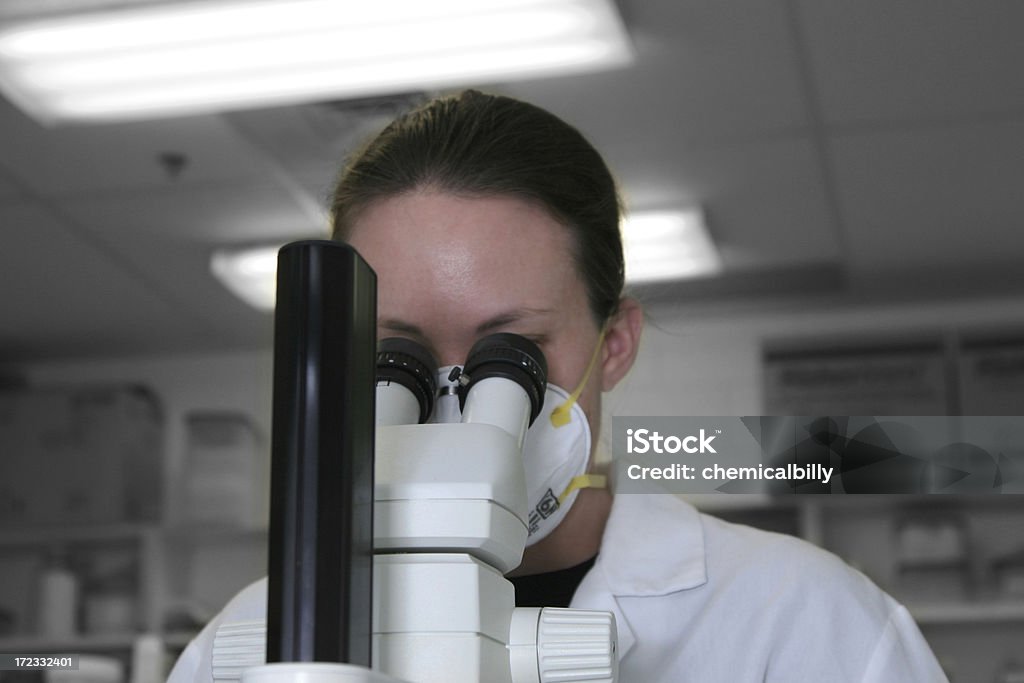 Microscope Scientist uses a dissecting microscope. Background set apart by use of black and white conversion. 20-24 Years Stock Photo