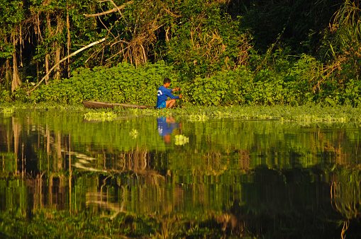 Pacaya-Samiria Nature Reserve, Amazon, Northeastern Peru, August 29, 2018\n\nA native or ribereno (riverside dweller) on a lagoon off of the Ucayali river in the Amazon just after sunrise. This Amazonian starts his day on the river in his boat working - fishing and growing & gathering crops along the shoreline.