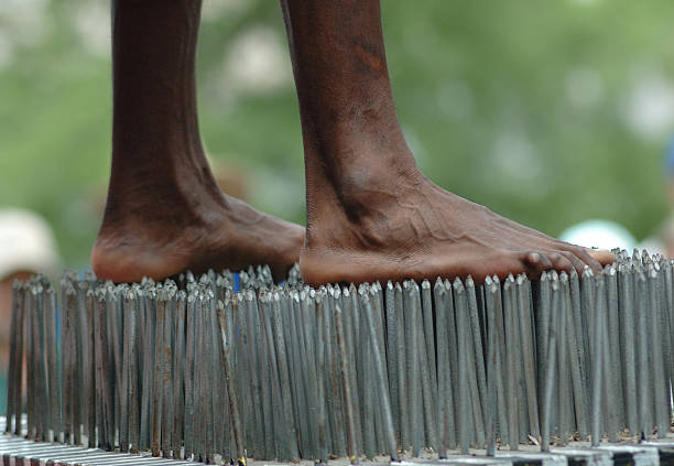 Bed of Nails Barefoot person standing on a bed of nails. bed of nails stock pictures, royalty-free photos & images