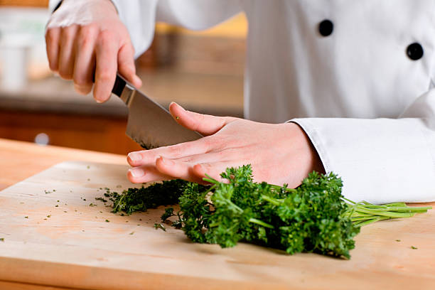 Chopping Herbs A chef's hands finely chopping herbs.  Shallow dof chervil stock pictures, royalty-free photos & images