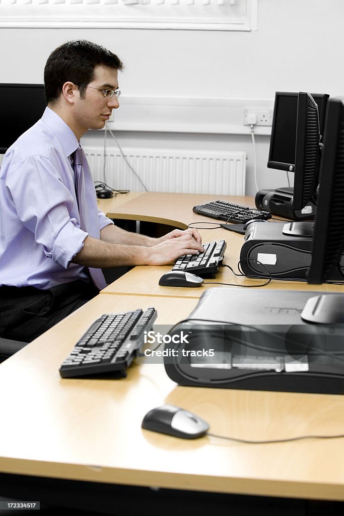 adult education: mature student working at his desk An IT professional rolls his sleeves up and gets down to the job at hand. 30-34 Years Stock Photo