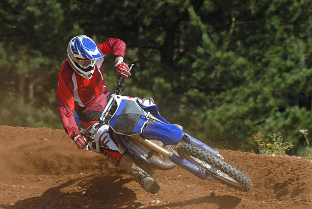 Cornering Dirtbike A dirtbike rider takes the top of the corner to get more grip bmx racing stock pictures, royalty-free photos & images