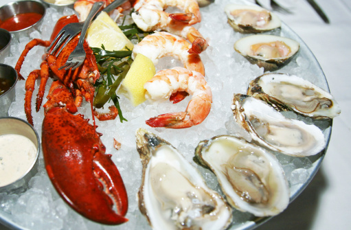Lobster, prawns and Oysters served on ice in plate.