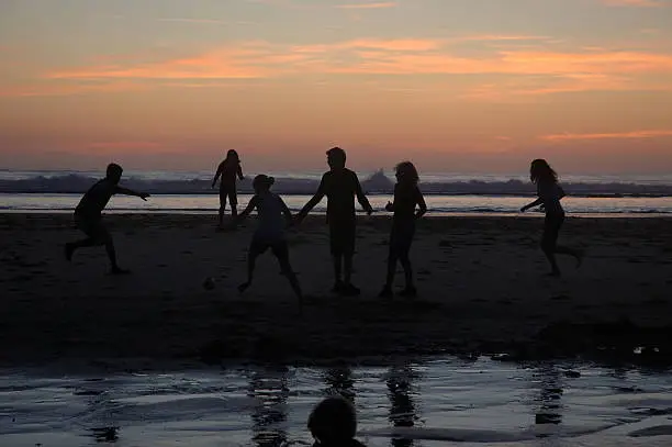 Some kids playing soccer on the beach with sundown in the backgroundMore images see: