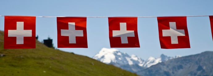 Swiss flag against top of Jungfrau (Switzerland), snow peak and blue sky background.