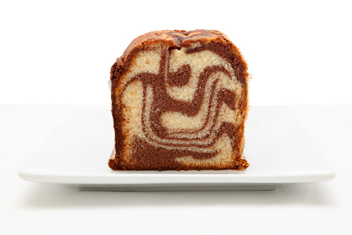 marble cake on square plate sitting on a textured surface isolated from white background - chocolate and vanilla flavour