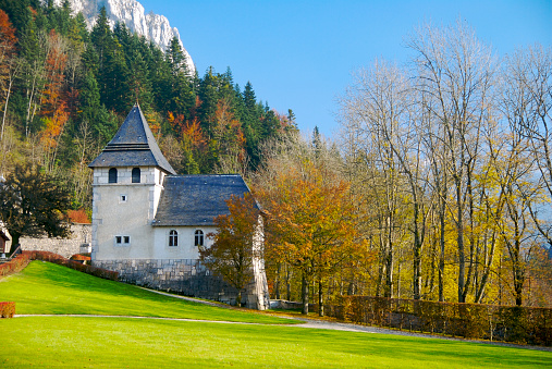 Idyllic little church in the heart of nature, scenic German Alps landscape in Berchtesgaden with mountains in the background, blue sky and lush trees