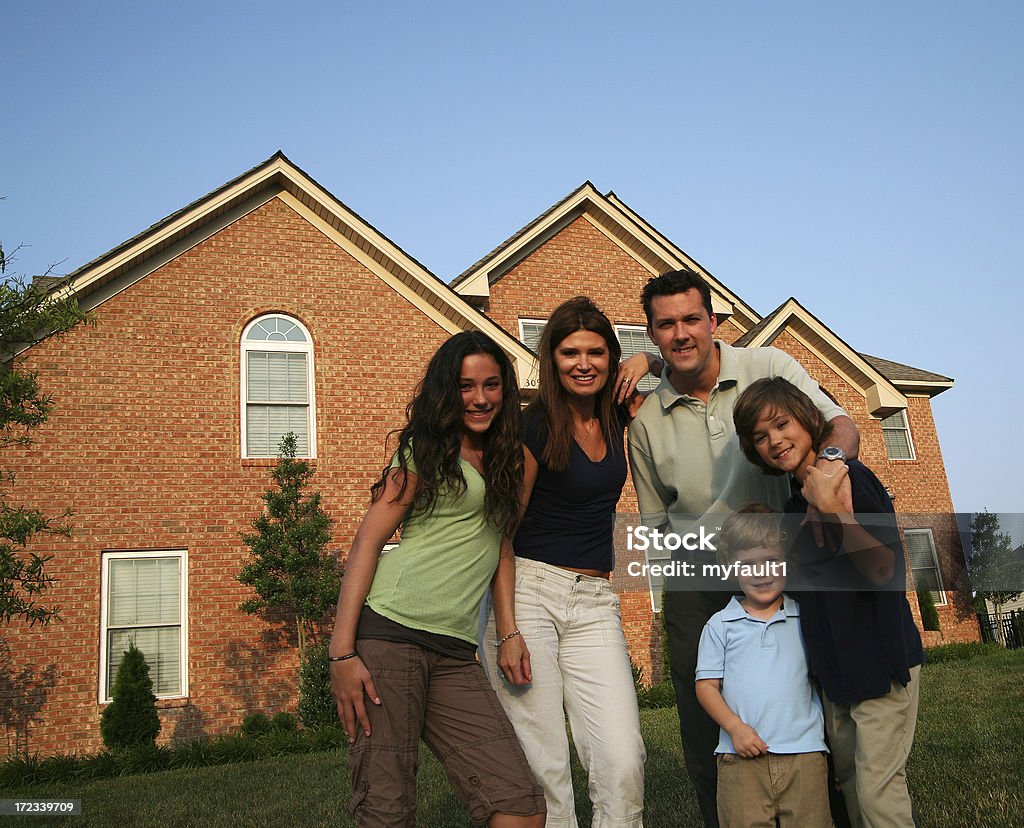 Family in front of house Family of five in front of their home. In Front Of Stock Photo