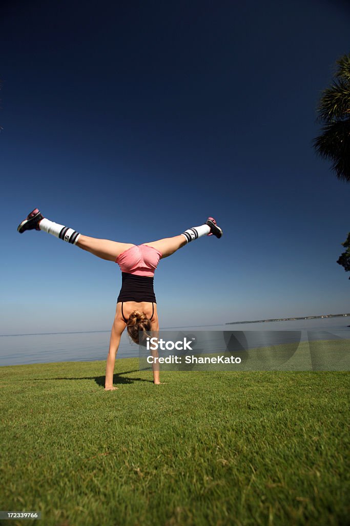 Flexível e atlética mulher fazendo uma estrela parada de mão sobre grama - Foto de stock de Esquisito royalty-free