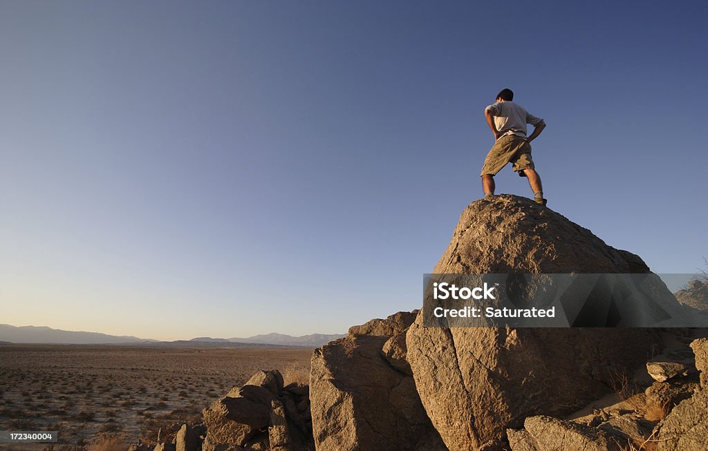 Uomo in piedi sulla roccia Vertice nel deserto - Foto stock royalty-free di Deserto