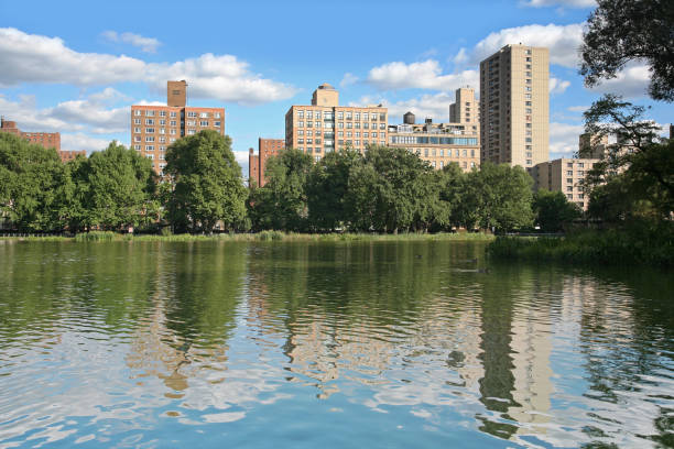 Lake With Skyline "Apartment buildings reflected in Harlem Meer, Central Park, New York City, NY, USA." harlem park stock pictures, royalty-free photos & images