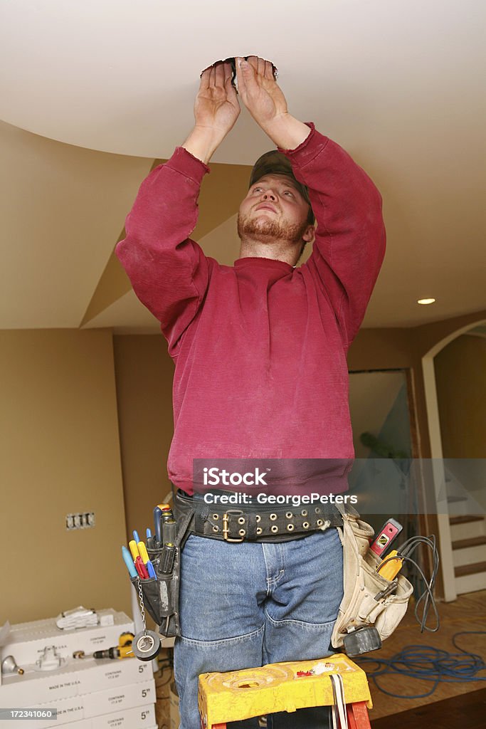 Electrician Electrician preparing to install can light in ceiling – searching for wires. Installing Stock Photo