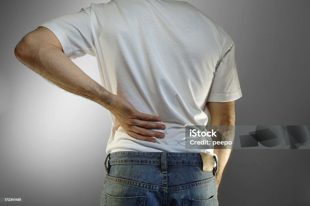 back pain man in white shirt and jeans holding lower back in pain Backache Stock Photo