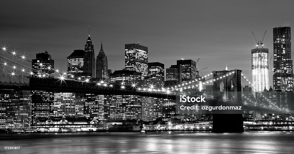 Brooklyn Bridge and Lower Manhattan View of Brooklyn Bridge and Downtown Manhattan as seen from Brooklyn Bridge Park over the East River at twilight. The New York City lights are visible. Black and white image taken with Canon Eos 5D Mark II and developed from raw Brooklyn Bridge Stock Photo
