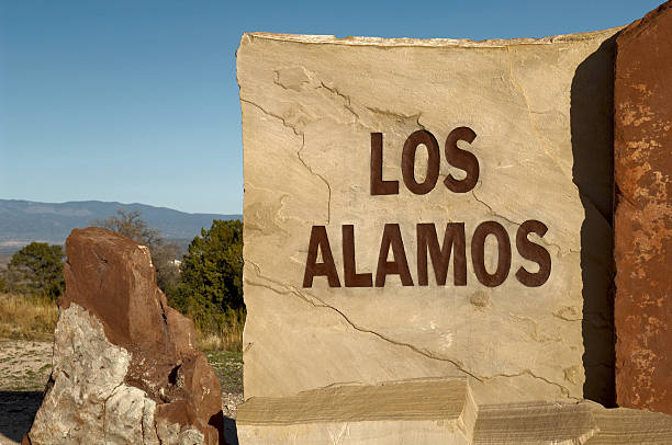 Atomic City Sign Four "The hard light of the setting sun casts harsh shadows on this carved and painted stone sign at the entrance to the town of Los Alamos, New Mexico, home to the Los Alamos National Laboratory, and birthplace of the Atomic Bomb. This image is one in a series on the LA Main Hill Entrance." los alamos new mexico stock pictures, royalty-free photos & images
