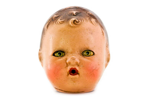 A creepy female doll head with yellow eyes Very old doll head against a white background. Shallow depth of field. doll stock pictures, royalty-free photos & images