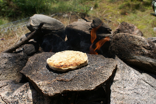 Bannock bread baked on a hot rock over a campfire.