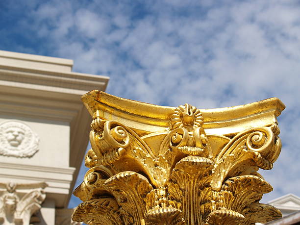 Golden pedestal below Greek style temple against cloudy sky.