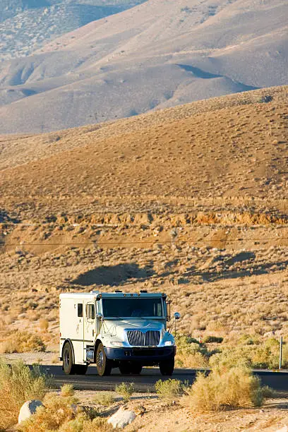 An armored truck heads down a desert road.