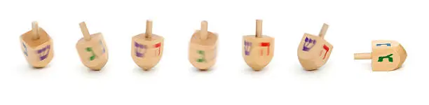 A dreidel spins 'round and 'round and  then falls. Motion blur on most of the spinning dreidels.