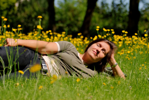 a woman lies on a wildflower meadow in the sun.