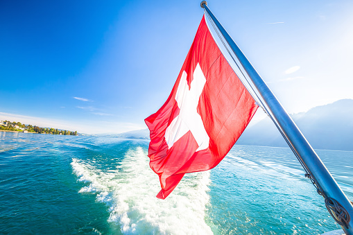 Switzerland flag on boat flowing Luzern lake, scenic landscape of Switzerland