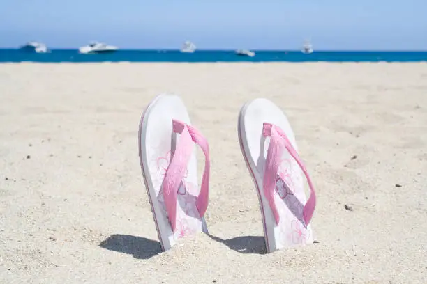 Two flip flops standing in the sand of a beach