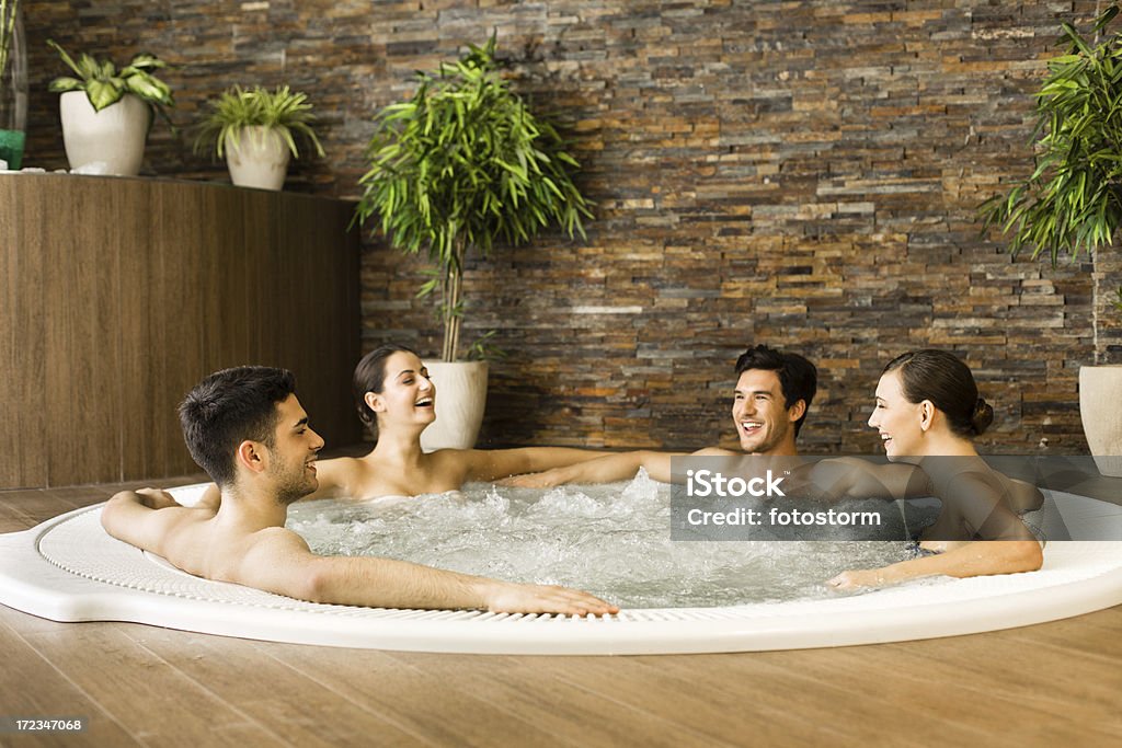 Amici che si diverte con vasca idromassaggio jacuzzi - Foto stock royalty-free di Piscina