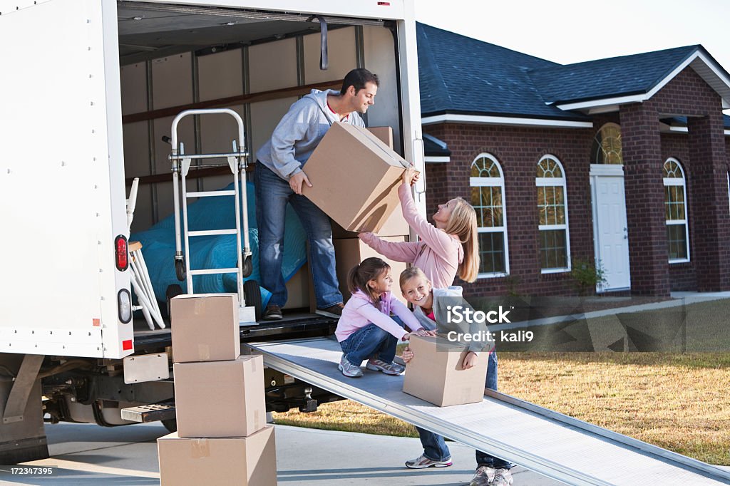 Family moving house, unloading truck Moving house.  Family loading or unloading moving van. Relocation Stock Photo