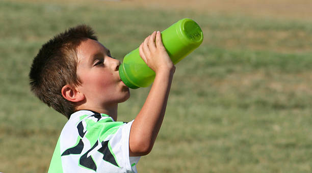 Ahhhhh!  Refreshing! Image of a young boy taking a drink from a water bottle. guzzling stock pictures, royalty-free photos & images