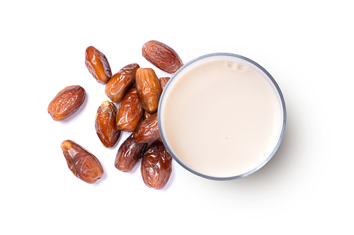 Date fruit and glass of milk isolated on white background. Top view, flat lay.