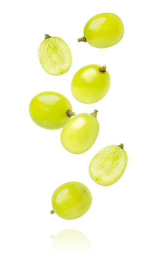 Green grape falling isolated on white background.
