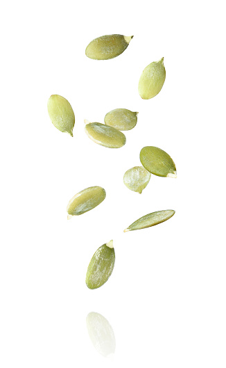 Pumpkin seeds flying in the air isolated on white background.