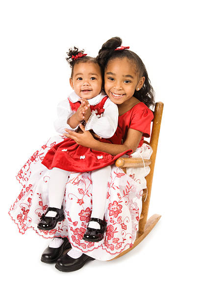Two sisters sitting in an antique rocking chair.