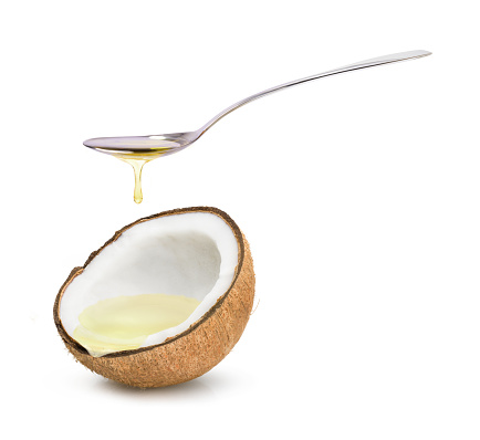 Coconut oil in spoon dripping and coconut fruit isolated on white background.