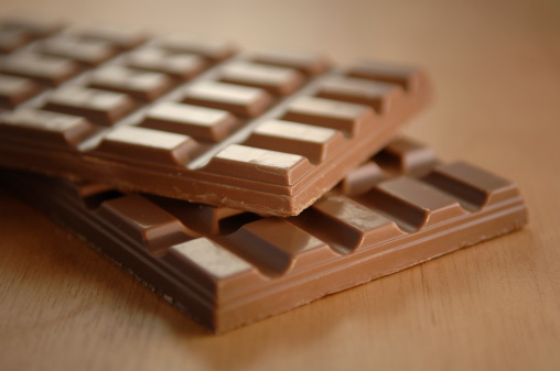 two chocolate bars on top of each other on wooden surface