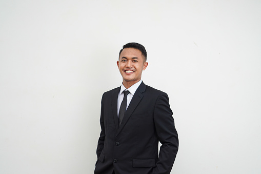 Portrait Young Asian businessman happy and smiling face look at camera hands in trouser pockets isolated on white background