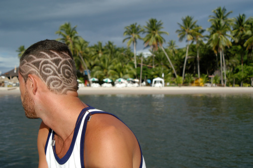 Free-form Afro-Brazilian hair carving mimics the background scene behind a tanned guy on a boat