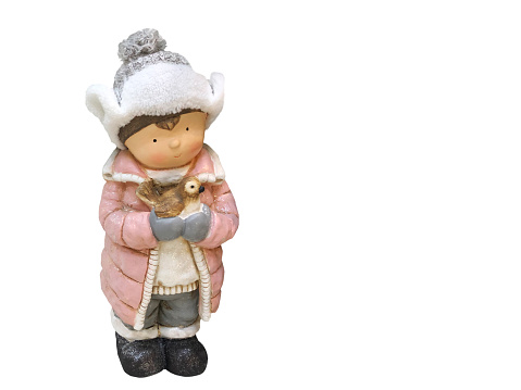 Cute decoration for the Christmas tree. A beautiful figurine of a little boy in warm clothes. who holds a bird in his hands on a white isolated background. Holiday, celebration, New Year, Noel concept.